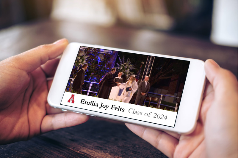 Mockup image of hands holding white mobile phone with graduation video clip playing